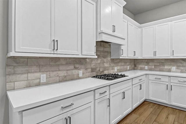 kitchen with light countertops, white cabinetry, gas cooktop, and backsplash