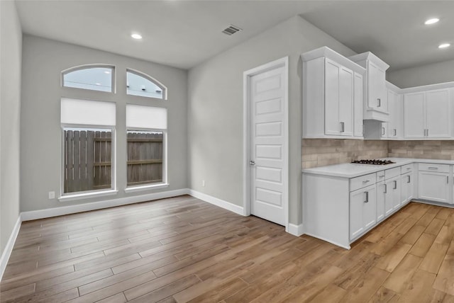 kitchen featuring visible vents, tasteful backsplash, light wood-type flooring, light countertops, and white cabinetry
