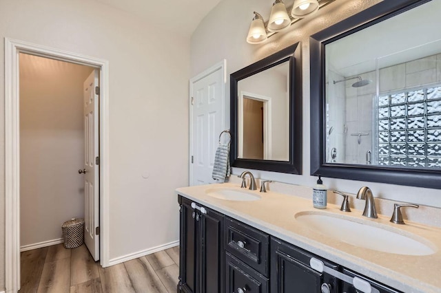 2106 Valerian Trl, Round Rock, TX 78665 - full bathroom with double vanity, tiled shower, wood finished floors, and baseboards