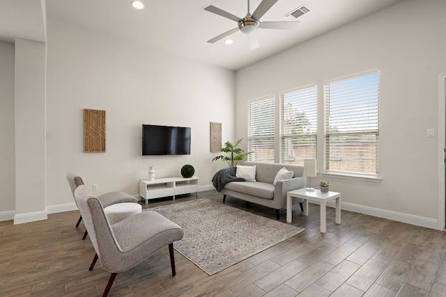 living room with baseboards, visible vents, wood finished floors, and ceiling fan