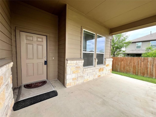 property entrance with fence and stone siding