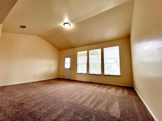 empty room with visible vents, carpet flooring, vaulted ceiling, and baseboards