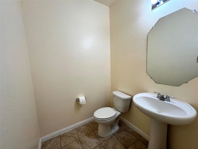 bathroom with toilet, tile patterned flooring, and baseboards