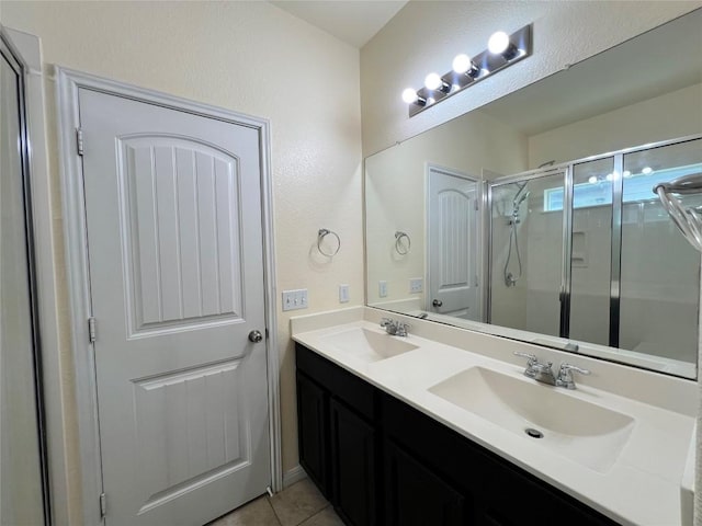 full bathroom featuring a stall shower, double vanity, a sink, and a textured wall