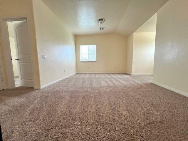 spare room with baseboards, visible vents, carpet floors, and vaulted ceiling