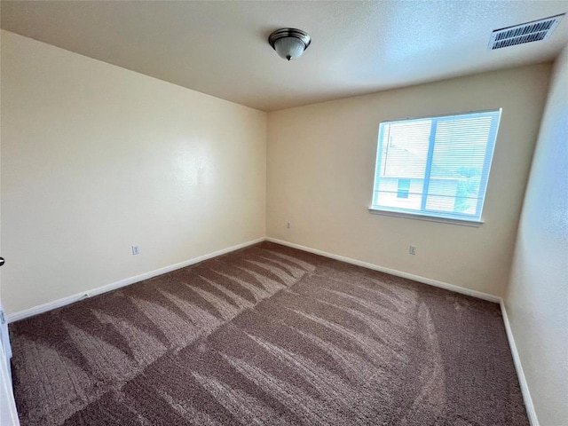 empty room with carpet, visible vents, and baseboards