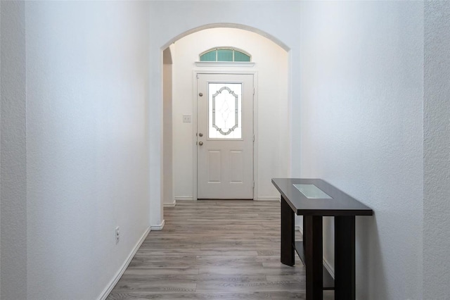 doorway with wood finished floors, baseboards, and arched walkways