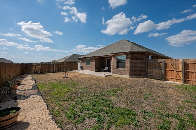 back of property featuring brick siding, a fenced backyard, and a patio area