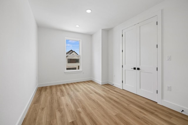unfurnished bedroom featuring baseboards, recessed lighting, a closet, and light wood finished floors