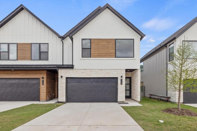 view of front of home featuring board and batten siding, stone siding, a front yard, concrete driveway, and an attached garage