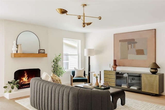 living area with an inviting chandelier, wood finished floors, and a warm lit fireplace