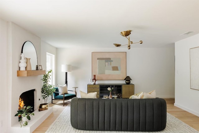 living area with baseboards, visible vents, light wood finished floors, and a fireplace