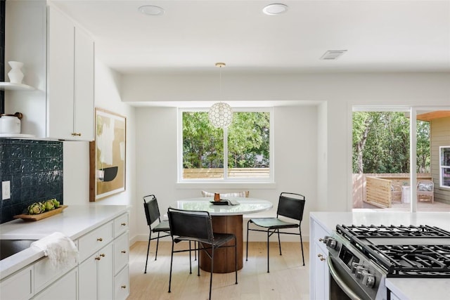 kitchen with white cabinets, gas stove, light wood-style flooring, and light countertops