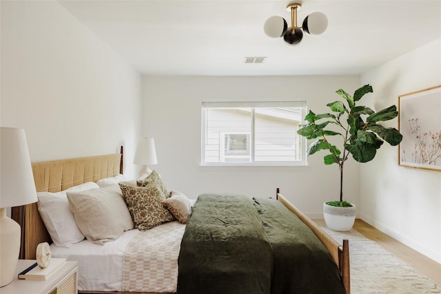 bedroom with baseboards, visible vents, and wood finished floors
