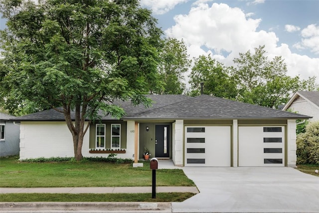 view of front of home featuring an attached garage, a front lawn, roof with shingles, and driveway
