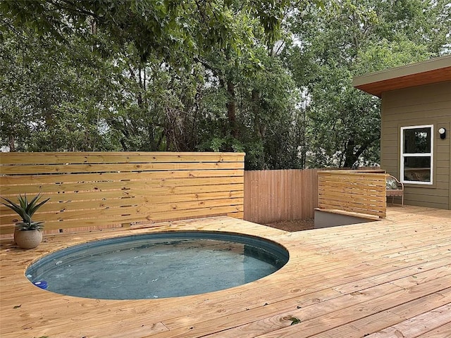 view of swimming pool featuring hot tub deck surround, fence, and a deck