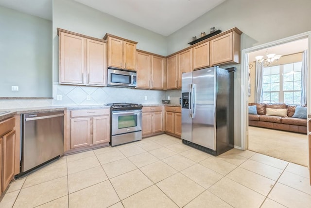 kitchen with light countertops, light tile patterned floors, backsplash, a notable chandelier, and stainless steel appliances