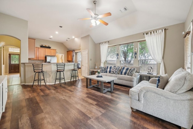 living area with visible vents, arched walkways, a ceiling fan, wood finished floors, and vaulted ceiling