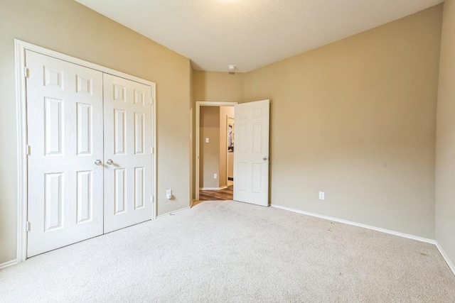unfurnished bedroom featuring carpet floors, baseboards, and a closet