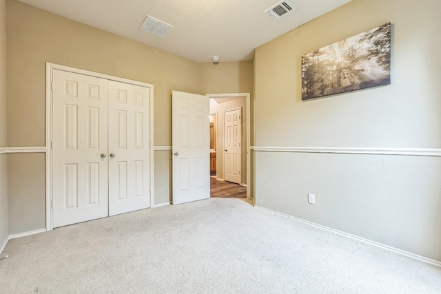 unfurnished bedroom featuring visible vents, carpet, baseboards, and a closet