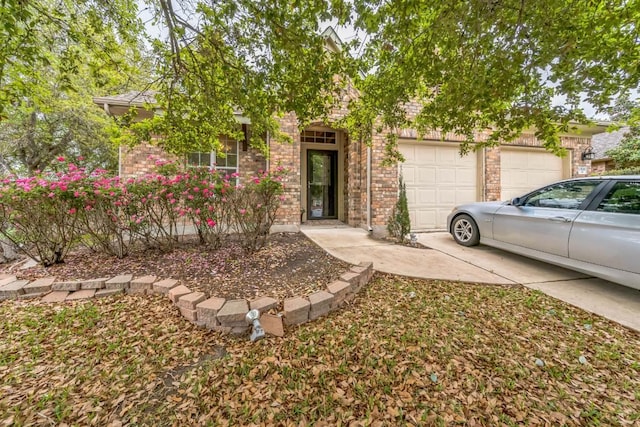 obstructed view of property with an attached garage, concrete driveway, and brick siding