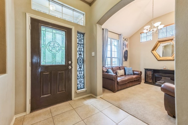 entrance foyer with light colored carpet, a notable chandelier, baseboards, light tile patterned floors, and lofted ceiling