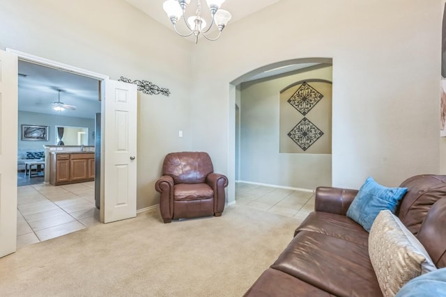 living area with an inviting chandelier, light carpet, baseboards, arched walkways, and light tile patterned floors