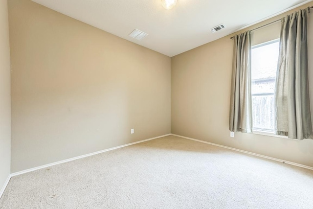 carpeted empty room featuring baseboards and visible vents