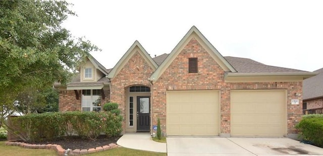 view of front of property with brick siding, driveway, and a garage