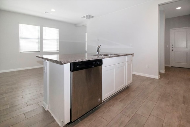 kitchen featuring stainless steel dishwasher, a kitchen island with sink, light wood-type flooring, white cabinetry, and a sink