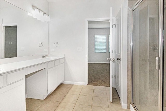 bathroom featuring a sink, tile patterned flooring, double vanity, baseboards, and a shower stall