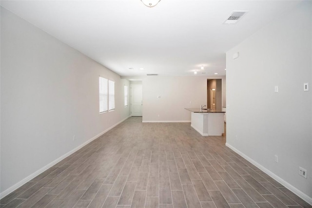 empty room featuring visible vents, baseboards, and light wood-type flooring