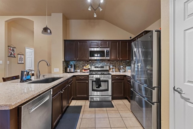 kitchen featuring backsplash, appliances with stainless steel finishes, a sink, a peninsula, and light tile patterned flooring