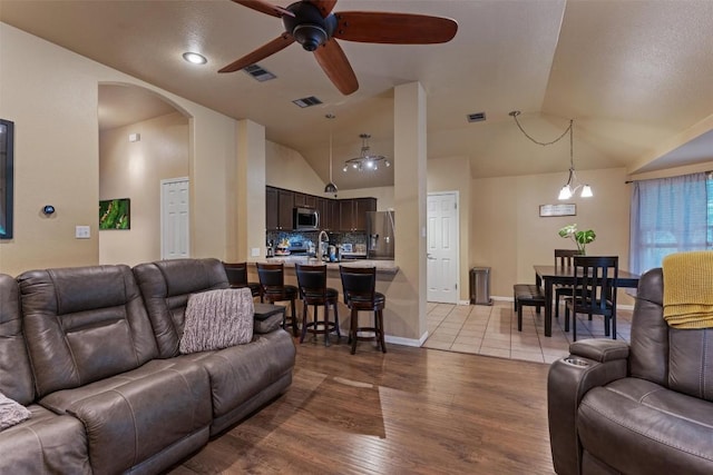 living room with visible vents, arched walkways, ceiling fan, and lofted ceiling