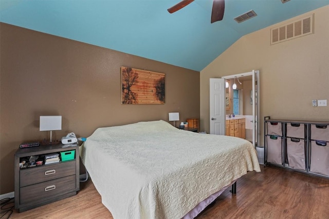 bedroom with ensuite bathroom, lofted ceiling, wood finished floors, and visible vents