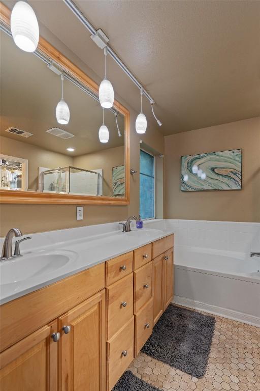 bathroom with a sink, a garden tub, double vanity, and visible vents