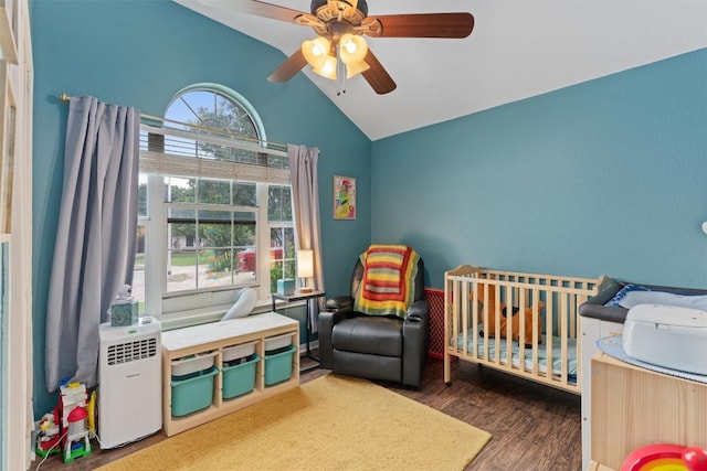 bedroom with a crib, ceiling fan, high vaulted ceiling, and wood finished floors