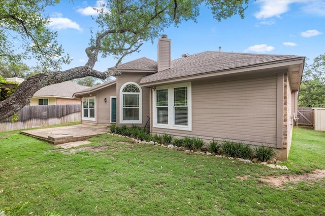 back of property with fence, a patio, a chimney, a shingled roof, and a yard