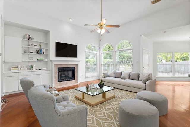 living area featuring ceiling fan, visible vents, wood finished floors, and a fireplace