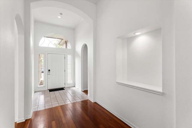 entryway with baseboards, arched walkways, and hardwood / wood-style floors