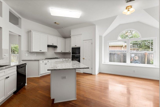 kitchen featuring dishwasher, white cabinetry, lofted ceiling, cooktop, and under cabinet range hood
