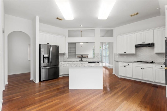kitchen with backsplash, visible vents, a sink, stainless steel fridge, and under cabinet range hood