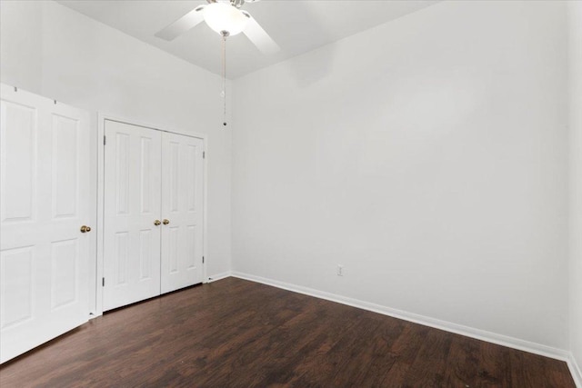unfurnished bedroom featuring baseboards, dark wood-style flooring, ceiling fan, and a closet
