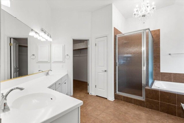 full bath featuring a relaxing tiled tub, a sink, tile patterned flooring, double vanity, and a shower stall