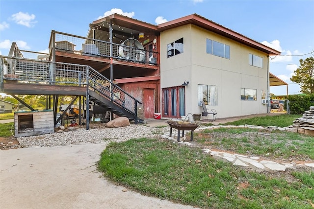 288 Ballard St, Tow, TX 78672 - back of property featuring a wooden deck, stairs, stucco siding, and an outdoor fire pit