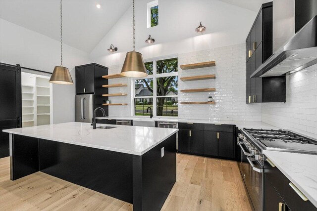 1105 Lipan Trl, Austin, TX 78733 - kitchen featuring dark cabinetry, open shelves, wall chimney range hood, high quality appliances, and high vaulted ceiling