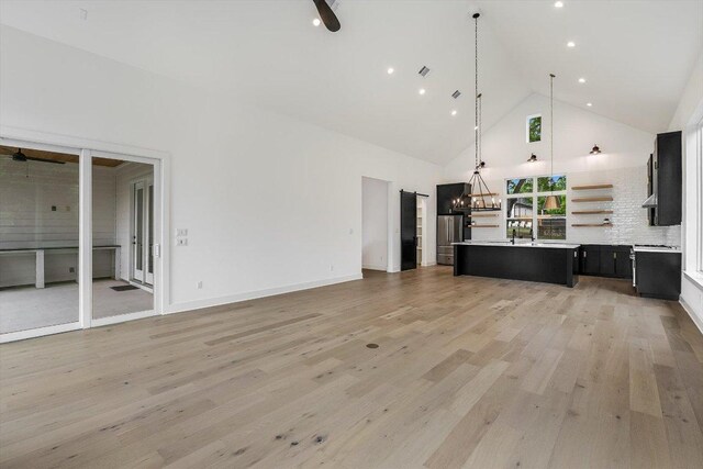 1105 Lipan Trl, Austin, TX 78733 - unfurnished living room with high vaulted ceiling, light wood-style flooring, a chandelier, a ceiling fan, and recessed lighting