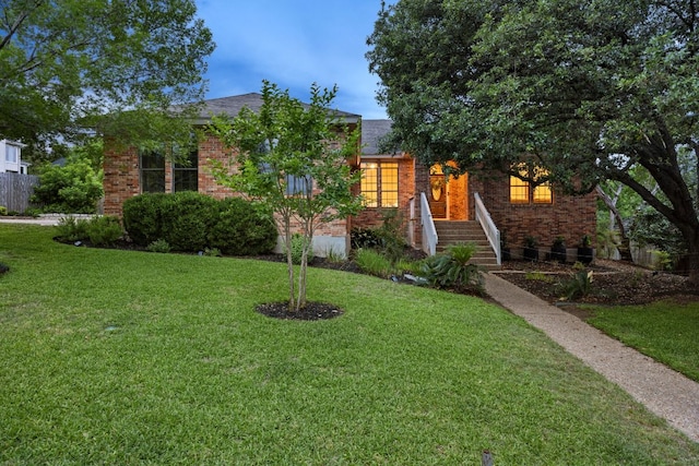 view of property hidden behind natural elements featuring brick siding and a front yard