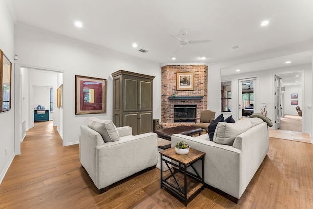 living room featuring a ceiling fan, visible vents, crown molding, a fireplace, and recessed lighting