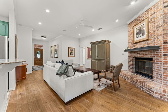 living area featuring light wood finished floors, a fireplace, recessed lighting, baseboards, and visible vents